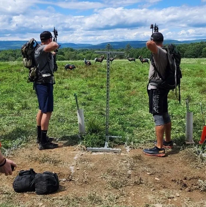 Two men working on an outdoor project involving a pole and wires.