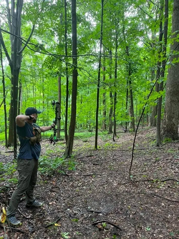 Person with a camera in a green forest, capturing nature.