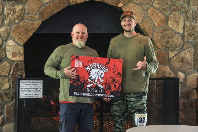 Competitors Jamie Withrow and Lucas Geiman posing with the Warhead Arrow Co poster at the 2026 Appalachian Bowhunter Challenge